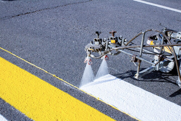 a team of workers drawing a pedestrian crossing in early spring using automated equipment on fresh asphalt