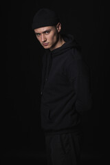 Portrait of a young sad guy in black clothes on a black background. Depressive portrait.