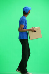 A male deliveryman, on a green background, full-length, with a box