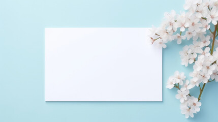 A blank white card surrounded by delicate white cherry blossoms against a soft blue background, perfect for a message.