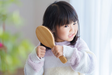 朝ヘアブラシでブラッシングする子供