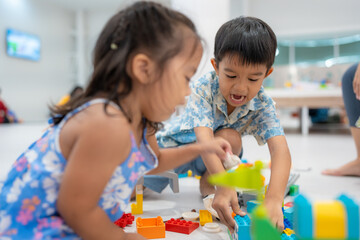 Adorable kindergarten kid asian boy and girl enjoying play colorful toy block