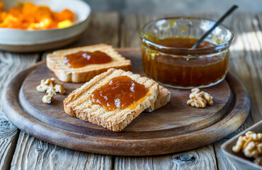 Rustic Pumpkin Jam Breakfast. Toasts with jam on wooden cutting board with jam jar
