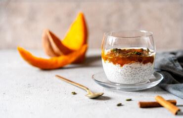 Healthy chia seed pudding topped with artisanal pumpkin jam or compote, served in a clear glass with cinnamon and pumpkin seeds.