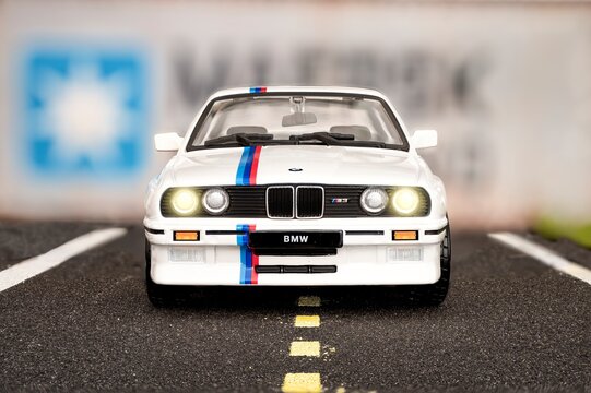 Madrid, Spain; 12-10-2023: Front view of scale model of a white Bmw M3 E30 sports car from the year 1986, simulating being on a road in front of ship containers