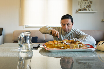 A man cuts a cream sponge cake on the table with a knife.