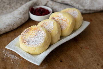 Plate of tasty cottage cheese pancakes with jam on wooden background