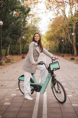 Portrait of smiling young latin woman riding an electric-bike in a park