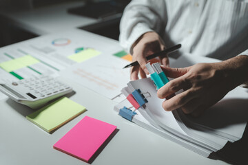 Auditor is working on accounting in the office, Businessman calculating the financial liquidity of the company, He was jotting down numbers from the company's financial documents.