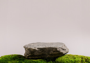 Dark Stone podium above green moss surface table on a beige pink background. Still life for the...