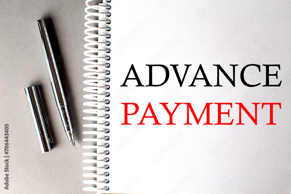 Poster advance payment text on a notebook with pen on grey background