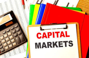 CAPITAL MARKETS text written on paper clipboard with chart and calculator