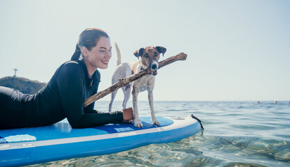 Sea woman sup. Silhouette of happy positive young woman with her dog, surfing on SUP board through...