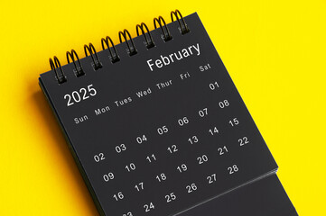 February 2025 black and white desk calendar on yellow cover background. Calendar concept