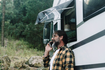 One man outside a motorhome do a phone call with a smile. People and alternative travel van life...