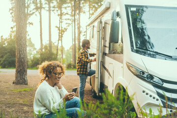 Couple enjoy travel destination in free parking in the mountain woods. Woman sitting outside using...