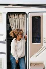 Happy traveler woman smiling and looking outside her camper van motorhome standing on the open...