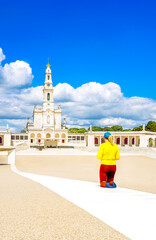Portugal, Fatima Sanctuary - Devoted pilgrim woman walking alone on knees in the Penitential Path at Fátima marian shrine square.