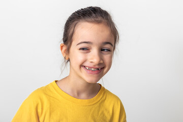 Funny little Caucasian girl smiles slyly on a white background isolated.