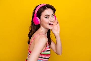 Portrait of good mood cute woman with piercing wear knit tank touch earphones enjoy sound isolated on vivid yellow color background