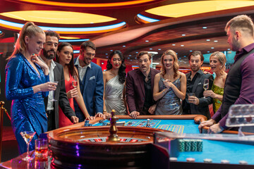 Multiethnic Young Adults Playing an Engaging Game of Roulette, Spending a Fun Evening in a Fancy Hotel Casino . Enthusiastic Gamblers Cheering Together, Congratulating a Happy Winner
