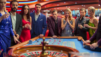 Casino Enthusiasts Making Calculated Bets at a Roulette Table. International Crowd of Young...