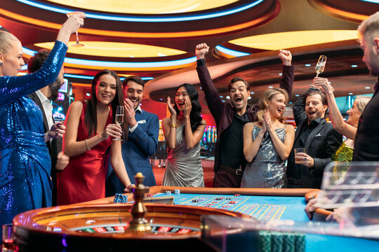 Group of Multiethnic Young Men and Women Entertaining Themselves with a Game of Roulette. Gamblers Spending an Evening in Casino. Players Cheering Together with Triumphant Winner