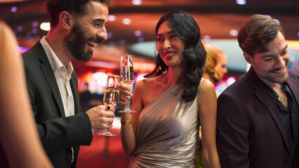 Multiethnic Couple Having a Fun Conversation at a Casino while Drinking Champagne and Gambling at a...