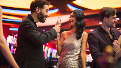 Multiethnic Couple Having a Fun Conversation at a Casino while Drinking Champagne and Gambling at a...