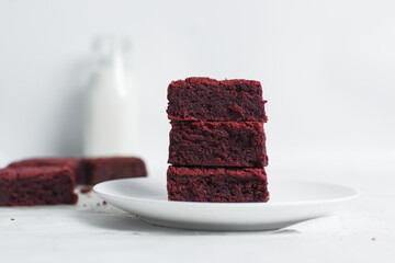 Fudgy red velvet brownies on a white plate, red velvet fudge brownies on a white background,...