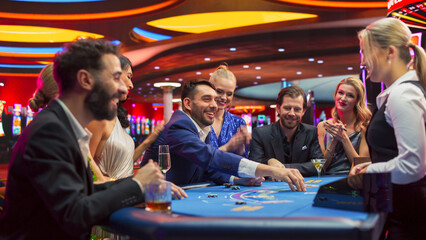 Group of Casino Goers Enjoying Time in a Modern Casino, Friends Placing Blackjack Bets,...