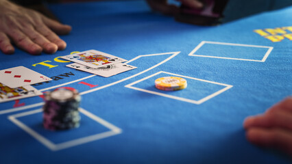 Close Up on Casino Baccarat Gambling Table: Anonymous Croupier Dealing Playing Cards on a Blackjack Table with Bet Chips in Place. Poker Chips are Being Exchanged as the Lucky Guest Wins the Jackpot