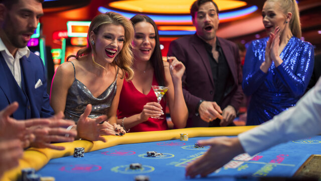 Happy and Cheerful Group of Casino Guests Placing Bets and Celebrating Winning Luck and Skill in Bacarrat. Glamorous Gamblers Having Fun, playing a Online Casino Card Game in Private Club