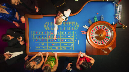 Top Down View: Luxurious Casino Male and Female Guests Putting Betting Chips on a Gambling Table, Trying to Predict the Outcome of a Roulette Game