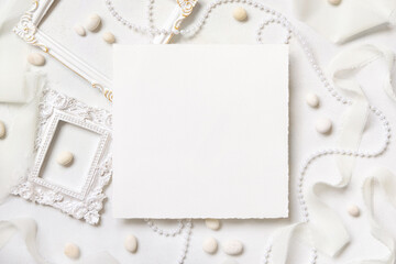 Blank card near white decorations, pebbles and silk ribbons top view, wedding mockup