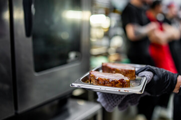 chef hand cooking pork meat in oven on kitchen