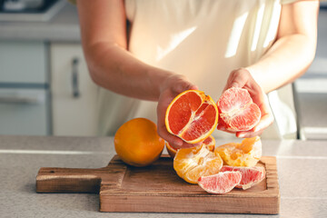 Peeled oranges in female hands and on a wooden cutting board for juice.