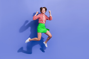 Fototapeta na wymiar Full length photo of satisfied girl wear green skirt jumping support favorite team clenching fists isolated on blue color background