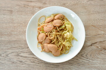 stir fried spaghetti with slice chicken sausage and cabbage in teriyaki Japanese sauce on plate  