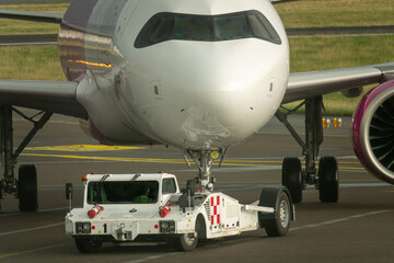 Tow tractor pushes the passenger airplane. Pushback tractor with Aircraft on the runway in airport.