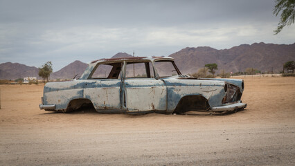 Ein blaues Autowrack ohne Reifen in der Wüste Namibias, Solitaire