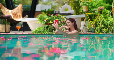 Indian Asian smiling young adult wet girl blue water pool edge take selfie record video use mobile...