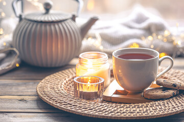 Cozy home composition with a cup of tea, candles and a teapot.