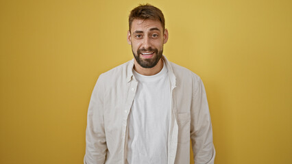 Cool and casual young hispanic man oozing serious, relaxed concentrate expression, looking handsome with beard, standing alone against isolated yellow wall background. male adult lifestyle portrait.