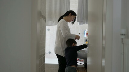 Candid mother and child standing in bathroom preparing to brush teeth together, domestic everyday lifestyle family activity, dental routine hygiene at home