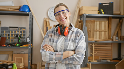Confident young woman with arms crossed wearing safety goggles and ear protection in a...