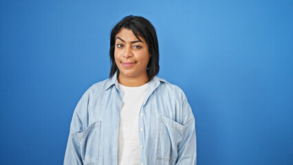 A confident middle-aged hispanic woman in casual attire poses against a blue isolated background