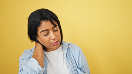 Hispanic adult woman with neck pain against yellow background