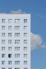 the pale blue facade of an apartment building against a clear sky