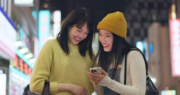 Friends, city and cellphone for social media, laughing and happy with mobile app comments. Japan, night and streaming online with technology, funny and meme humour with japanese communication